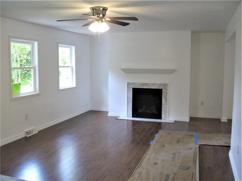 3903 Zimmerly Road Erie, PA 16506 - Photo 6 of 25 an empty room with wooden floor a chandelier fan and a fireplace