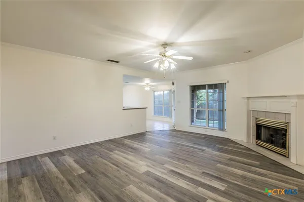 an empty room with wooden floor fireplace and chandelier fans