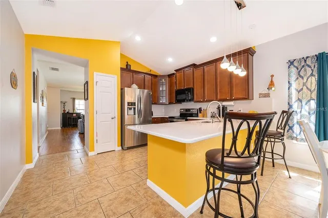 a kitchen with stainless steel appliances kitchen island granite countertop a refrigerator and a stove top oven