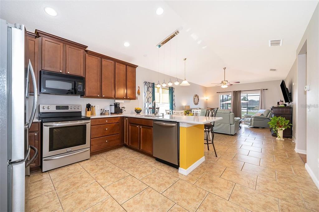 3406 Brant Street St. Cloud, FL 34772 - Photo 15 of 33 a kitchen with stainless steel appliances kitchen island granite countertop a refrigerator a stove top oven and a sink with dishwasher