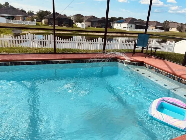 a view of a swimming pool with a yard and wooden deck