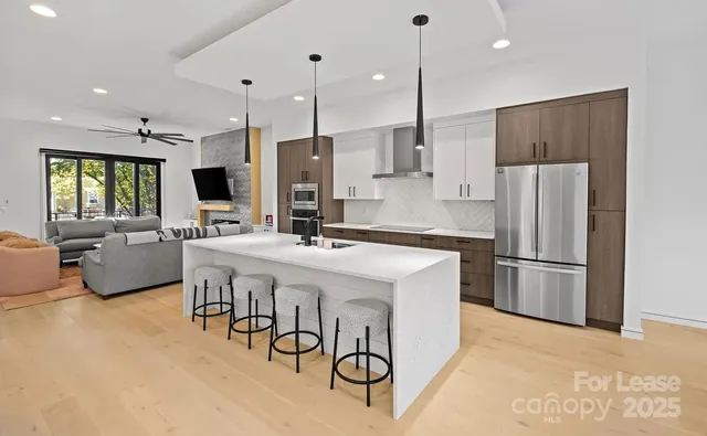 a kitchen with stainless steel appliances a refrigerator a stove a sink dishwasher with a dining table and chairs with wooden floor