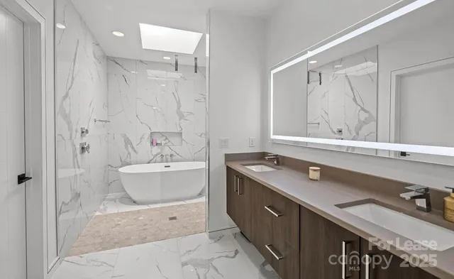 a spacious bathroom with a double vanity sink mirror and bathtub