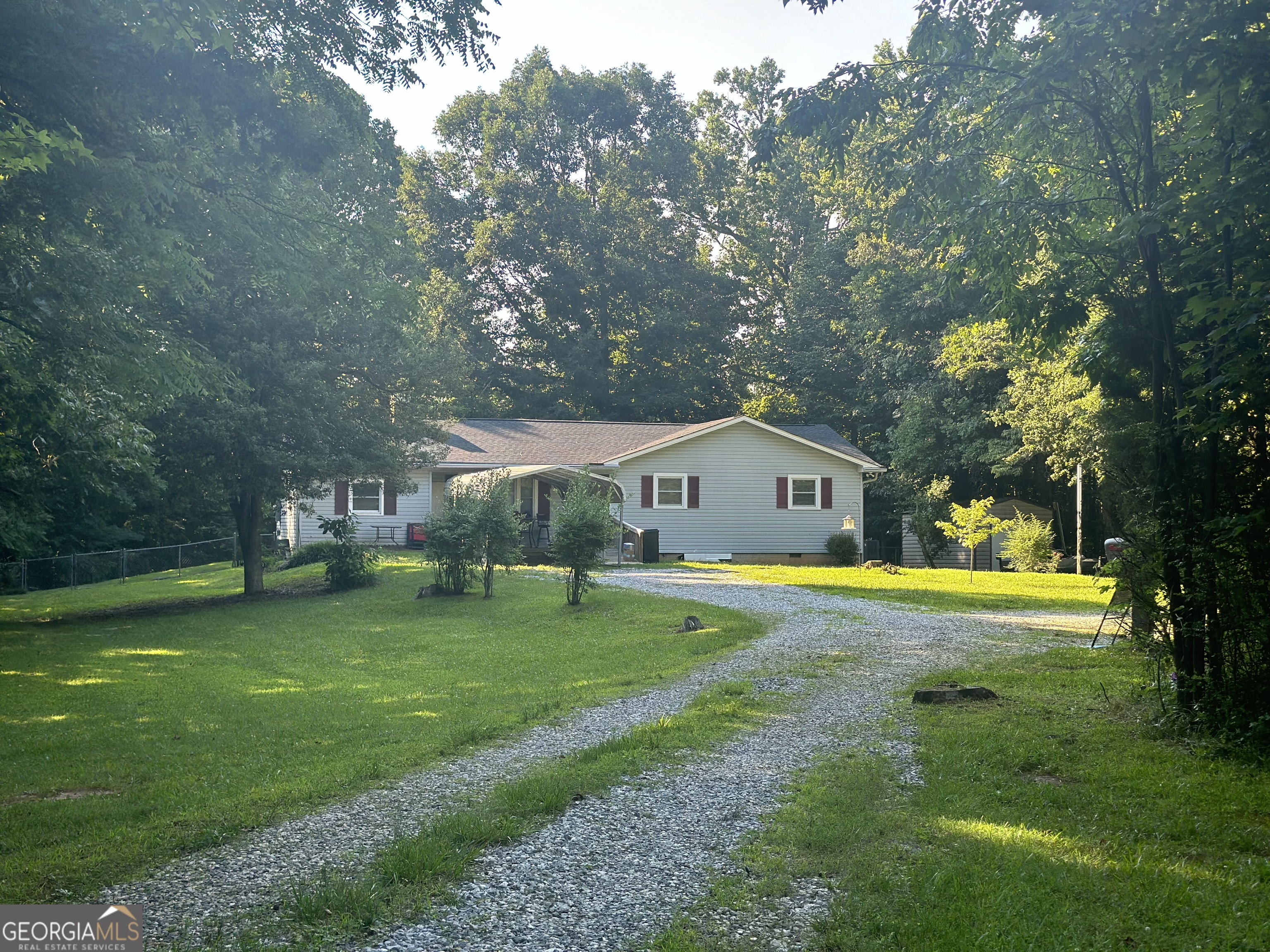 a view of a house with a big yard and large trees