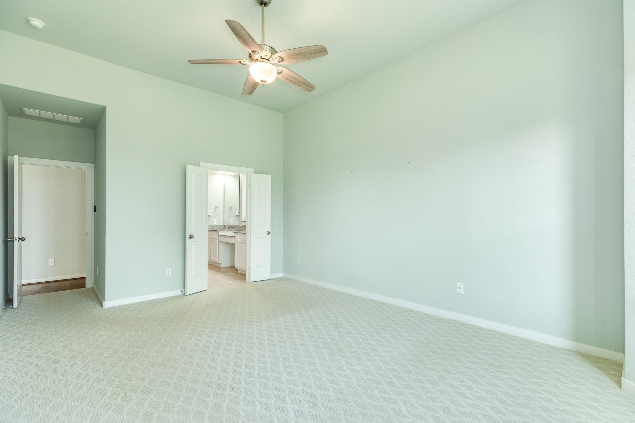 4015 Shackleton Court Iowa Colony, TX 77583 - Photo 17 of 50 Spacious primary bedroom featuring plush carpeting, a ceiling fan, and elegant double-door entry to the primary bathroom. This retreat is situated at the back of the home, offering serene, private views of the backyard and tranquil waterfront.