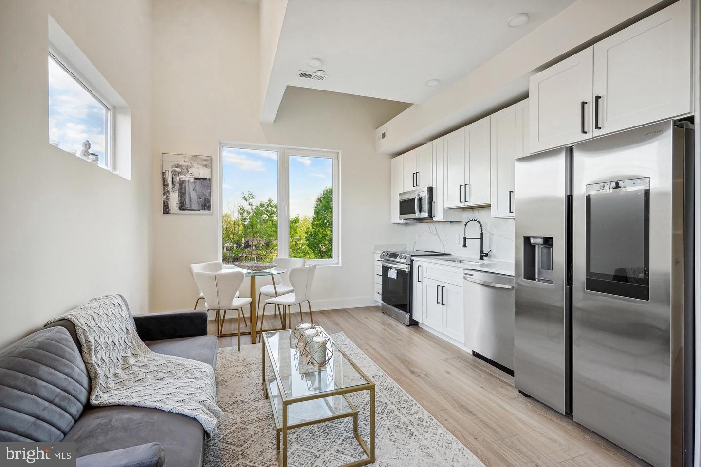 a kitchen with stainless steel appliances granite countertop a refrigerator a stove a sink dishwasher a dining table and chairs with wooden floor