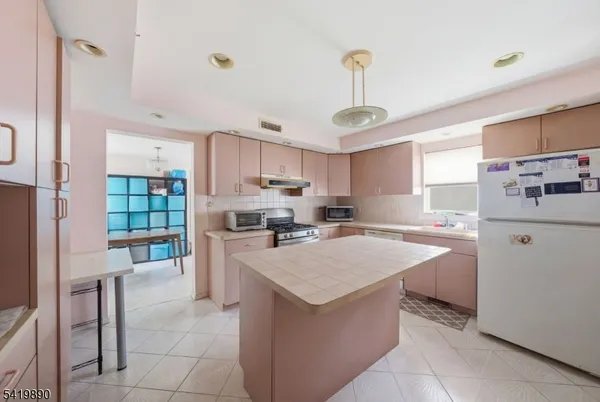 a kitchen with a refrigerator a stove top oven a sink dishwasher and white cabinets next to a window