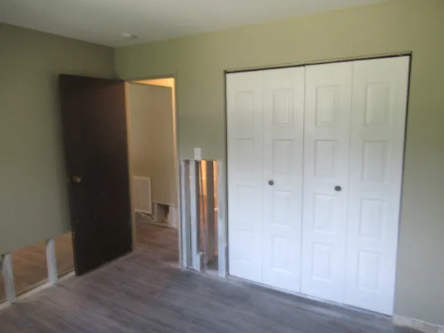 a view of an empty room with wooden floor and closet