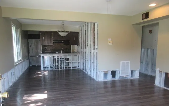 a view of a dining room with wooden floor fire place and kitchen view