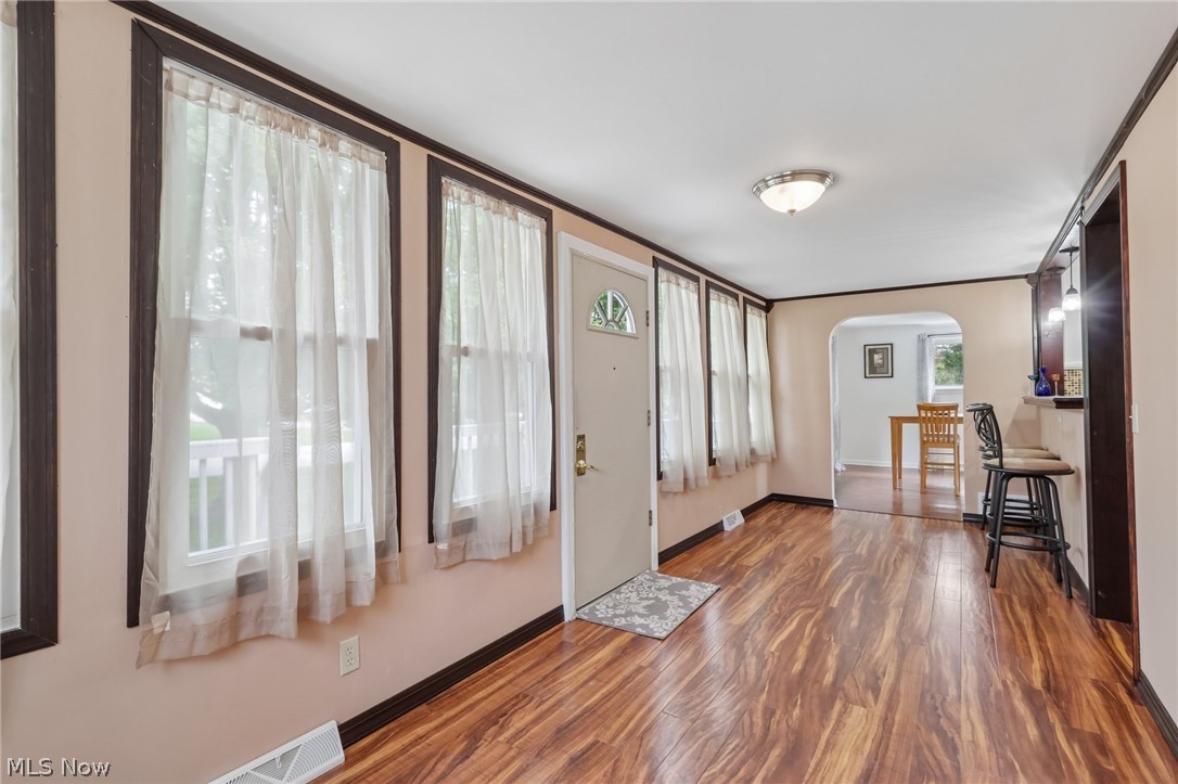 4188 Manchester Road Perry, OH 44081 - Photo 7 of 41 Wood-finish flooring throughout, multiple windows, archway opening to an additional room, and a ceiling-mounted light fixture