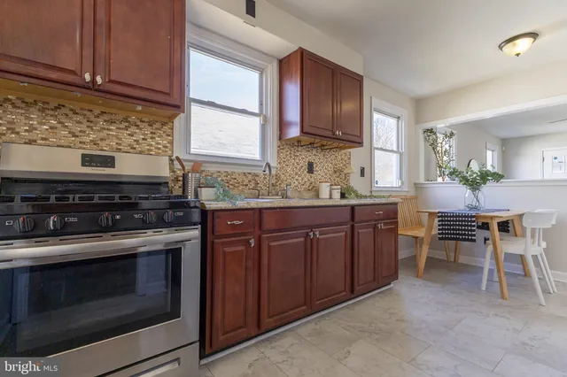 a kitchen with stainless steel appliances granite countertop a sink a stove top oven a dining table and chairs