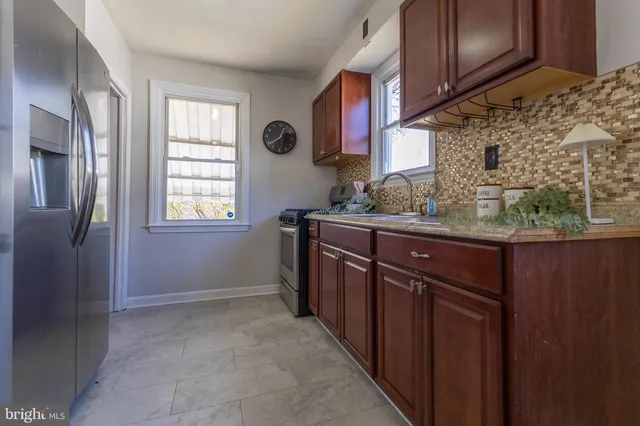 a kitchen with stainless steel appliances granite countertop a sink a stove a refrigerator and a window