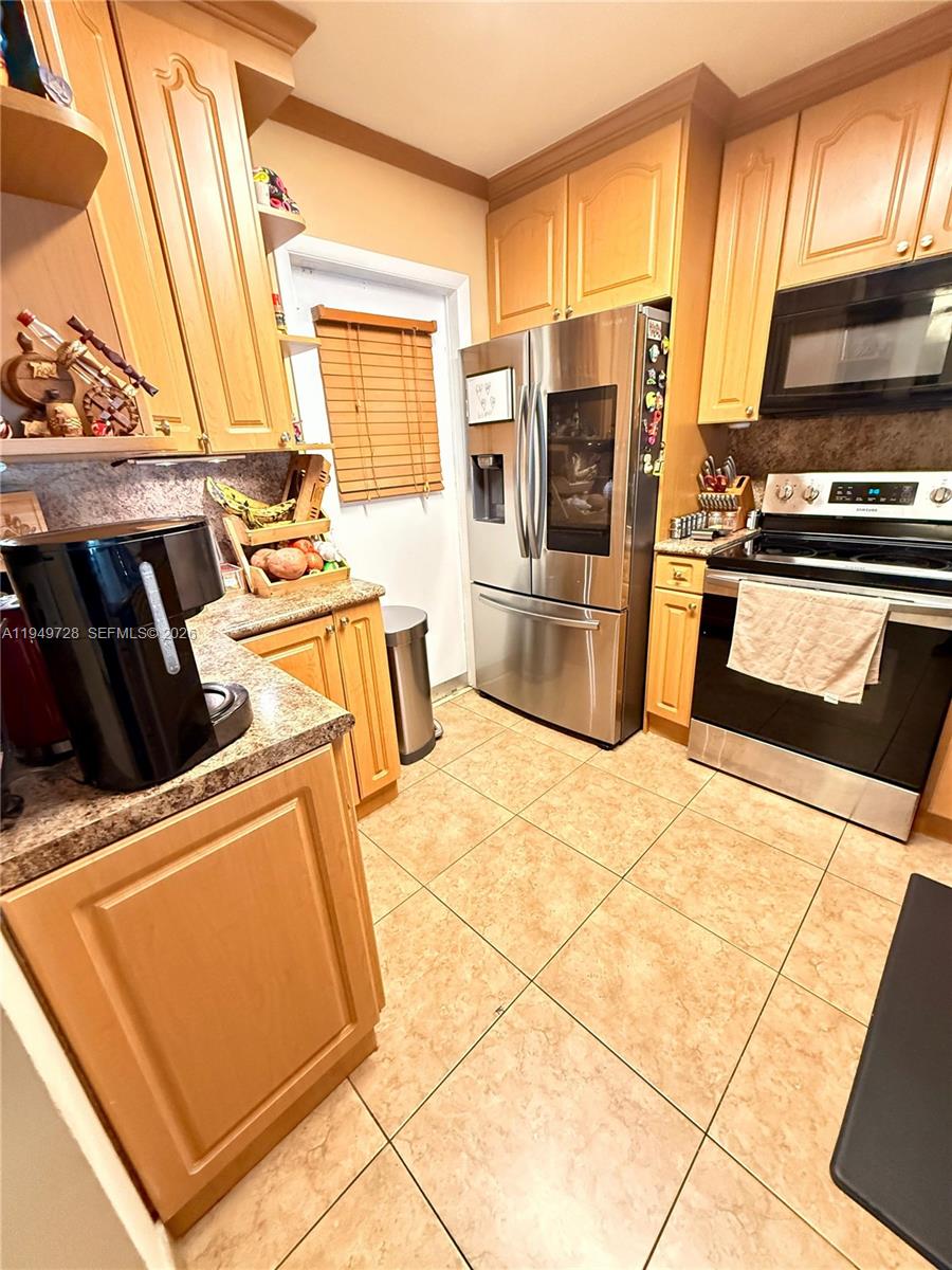 5790 Stirling Road, Unit 104 Hollywood, FL 33021 - Photo 4 of 19 a kitchen with stainless steel appliances kitchen island a stove a refrigerator and a sink
