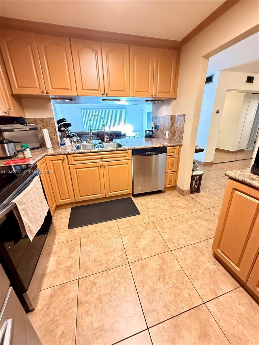 5790 Stirling Road, Unit 104 Hollywood, FL 33021 - Photo 6 of 19 a kitchen with stainless steel appliances kitchen island granite countertop a sink dishwasher and cabinets