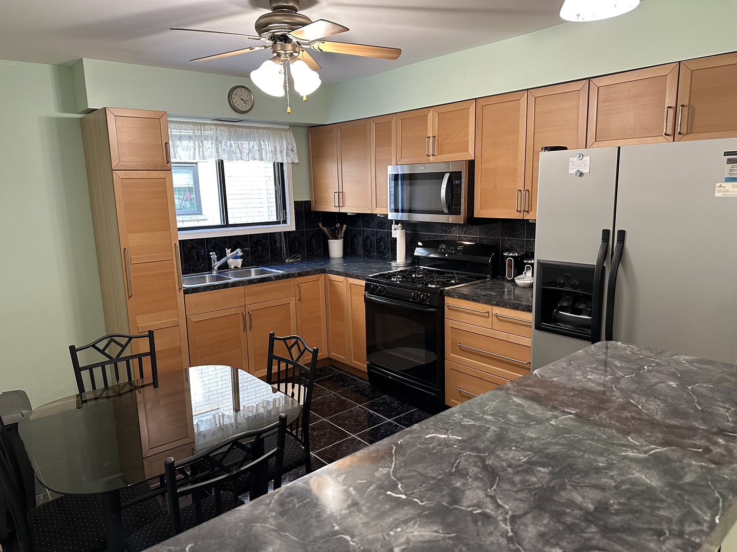 5155 North East River Road, Unit 116E Chicago, IL 60656 - Photo 4 of 10 a kitchen with stainless steel appliances granite countertop a stove refrigerator a sink dishwasher a dining table and chairs with wooden floor