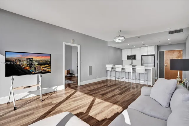 a kitchen with stainless steel appliances refrigerator wooden floor dining table and chairs