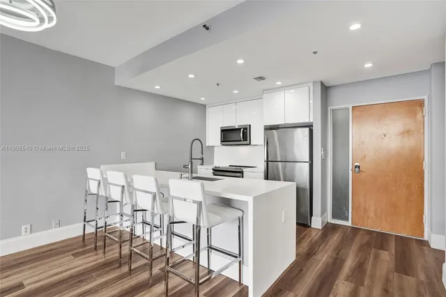 a large kitchen with dining table chairs and refrigerator