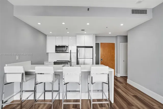 a kitchen with stainless steel appliances granite countertop a dining table chairs and white cabinets