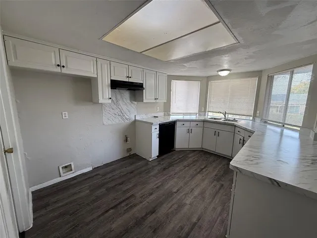 a kitchen with stainless steel appliances a sink cabinets and wooden floor