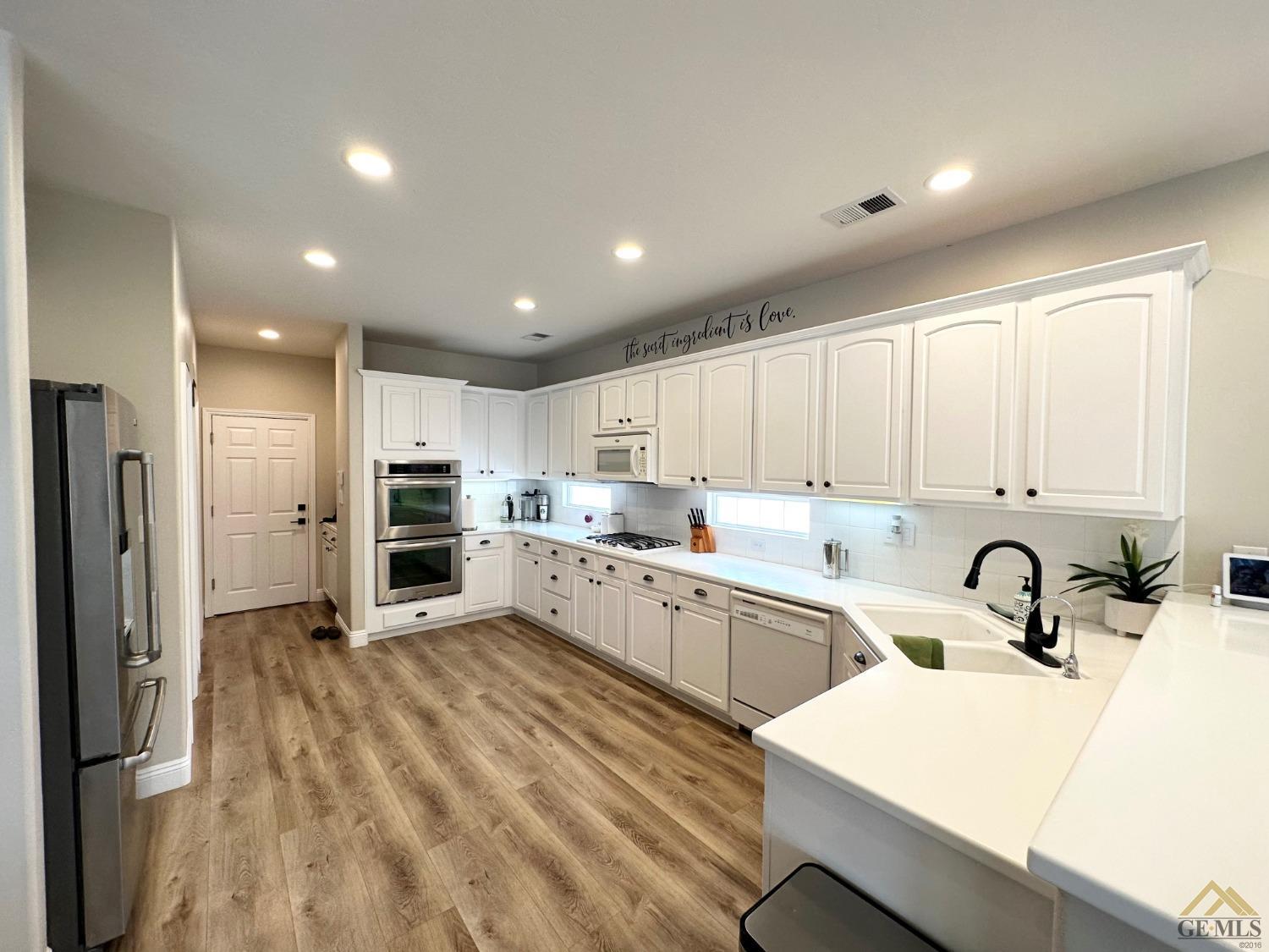 Undisclosed Address Bakersfield, CA 93311 - Photo 8 of 30 a kitchen with white cabinets and stainless steel appliances