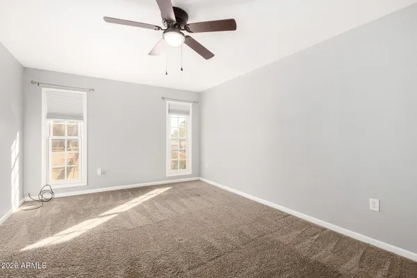 an empty room with windows and fan