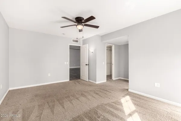 a view of an empty room with a chandelier fan