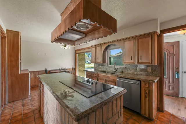 a kitchen with stainless steel appliances granite countertop a sink a stove and a wooden cabinets