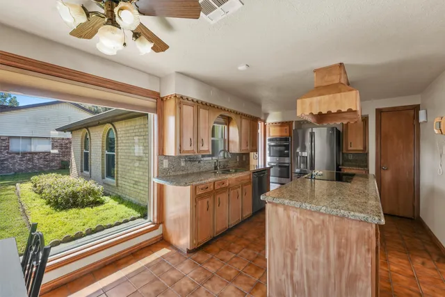 a kitchen with stainless steel appliances granite countertop sink stove and refrigerator