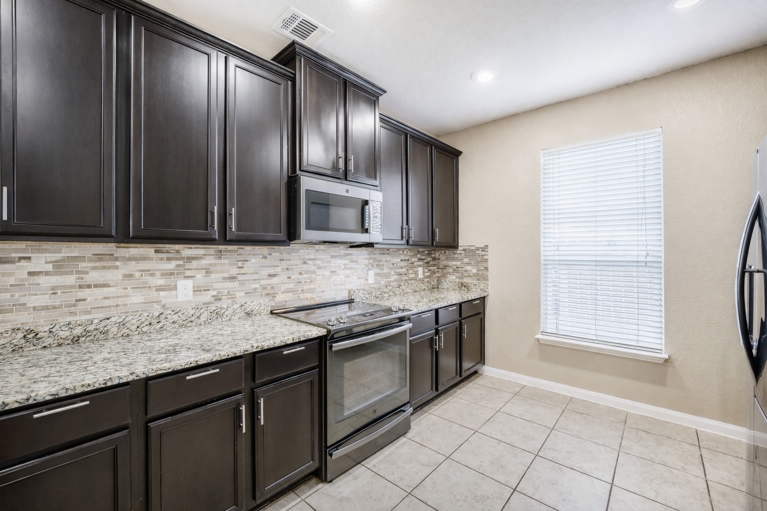 19621 Woodrow Wilson Street Manor, TX 78653 - Photo 10 of 34 a kitchen with stainless steel appliances granite countertop a sink stove and cabinets