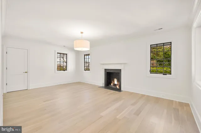 an empty room with windows and fireplace