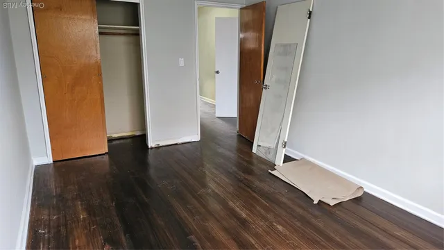 an empty room with wooden floor and entrance