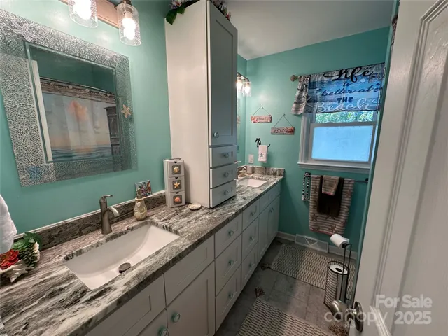 a bathroom with a granite countertop double vanity sink and a mirror