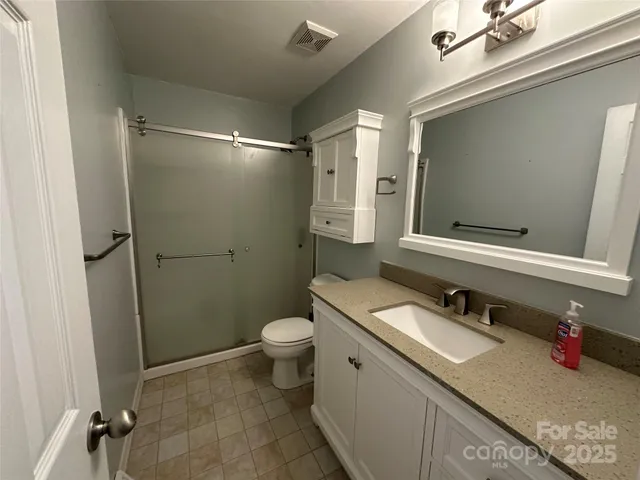 a bathroom with a granite countertop sink toilet and shower
