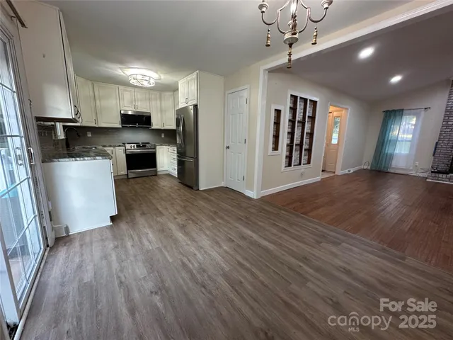 a view of a kitchen with a sink a refrigerator a ceiling fan and wooden floor