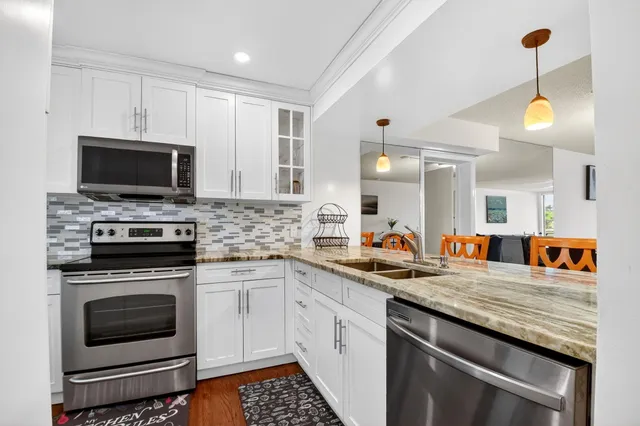 a kitchen with stainless steel appliances granite countertop a stove top oven a sink and a refrigerator