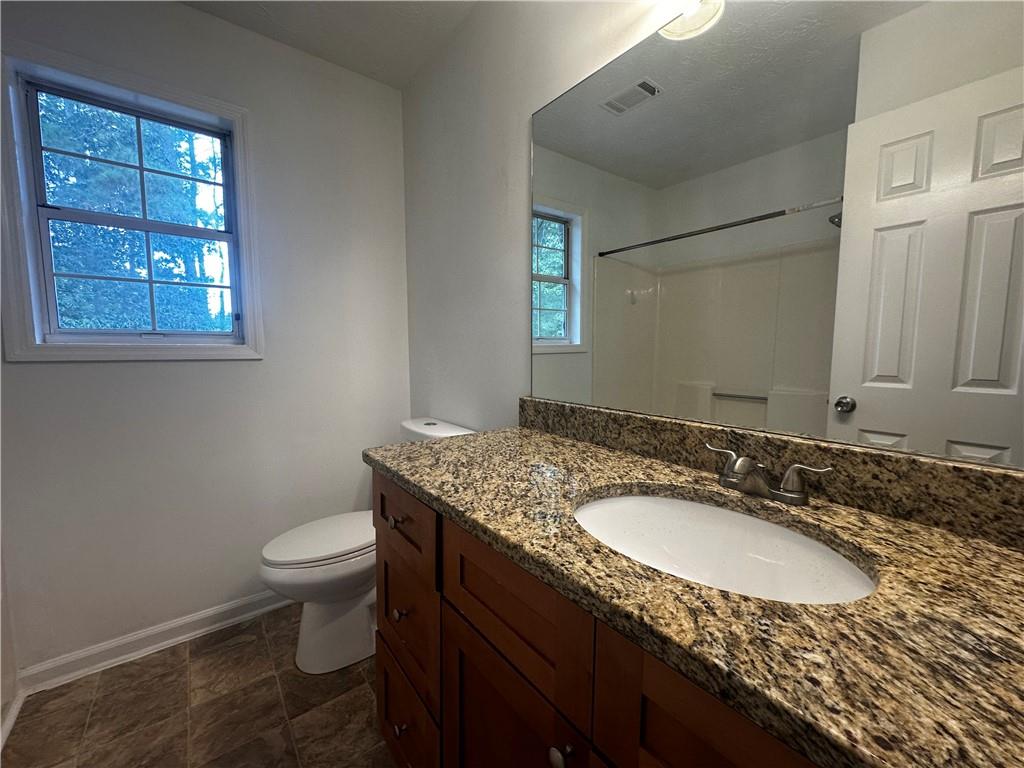 2536 Country Lake Circle Powder Springs, GA 30127 - Photo 20 of 25 a bathroom with a granite countertop sink toilet and mirror