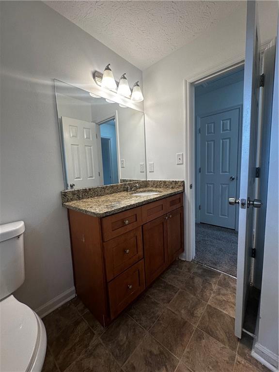 2536 Country Lake Circle Powder Springs, GA 30127 - Photo 21 of 25 a bathroom with a granite countertop sink a toilet a mirror and shower