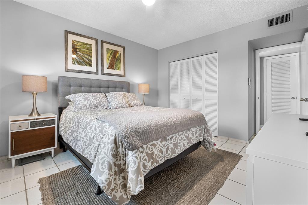 3216 Southeast 8th Street, Unit 303 Pompano Beach, FL 33062 - Photo 17 of 54 a bedroom with a bed and a lamp on table