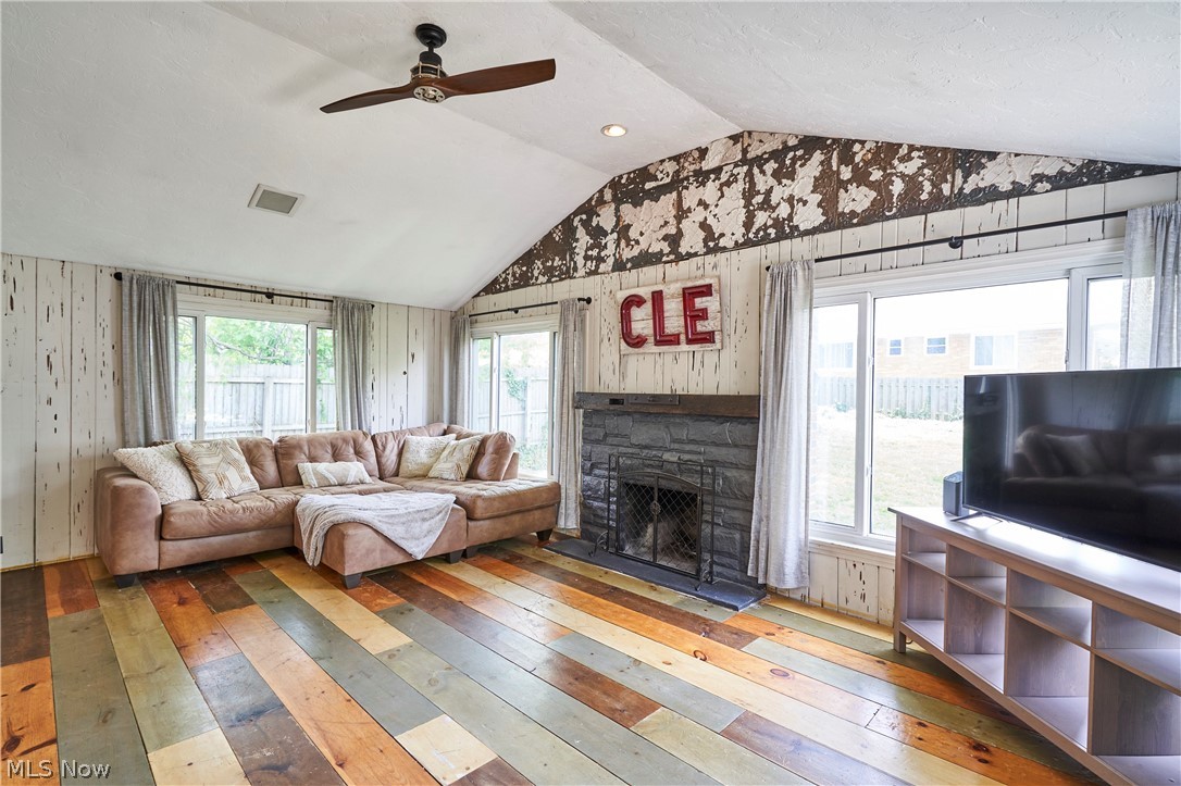 780 Bates Road Rocky River, OH 44116 - Photo 7 of 35 Vaulted living area featuring multi-toned wood-finish flooring, shiplap wall accents, and a stone-clad fireplace with a wood mantel