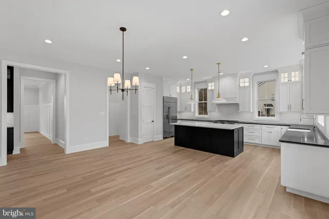 a large kitchen with granite countertop a large counter top a refrigerator and cabinets