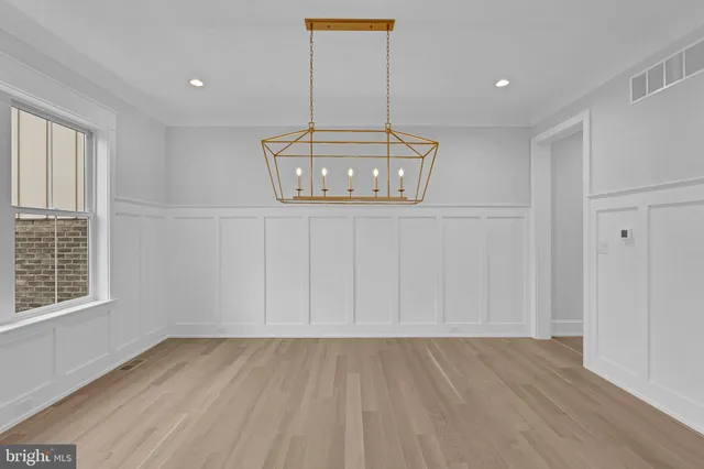 a view of an empty room with wooden floor and window