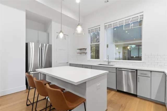 a kitchen with stainless steel appliances a dining table chairs and wooden floor