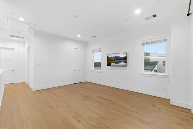 a view of empty room with wooden floor and windows