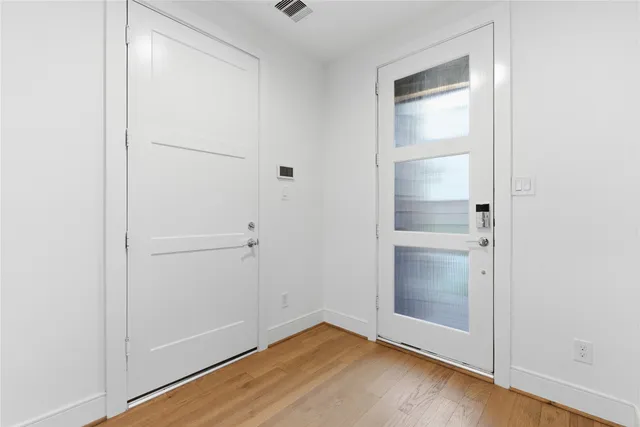 a view of an empty room with closet and wooden floor