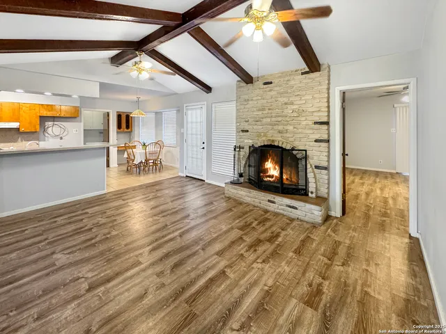 an empty room with wooden floor fireplace and windows