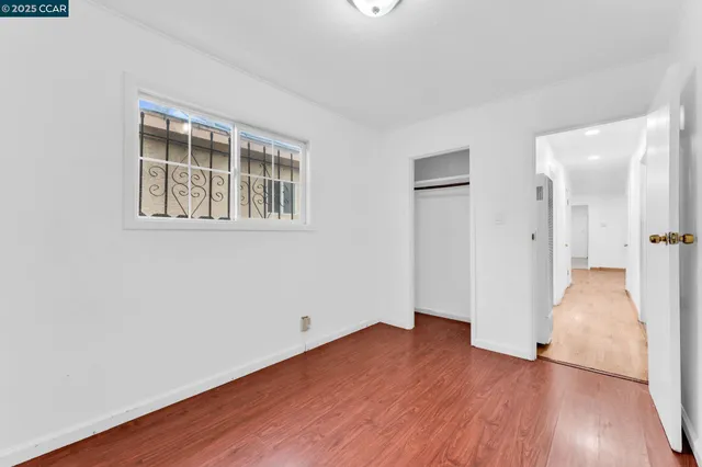 a view of empty room with wooden floor and a window