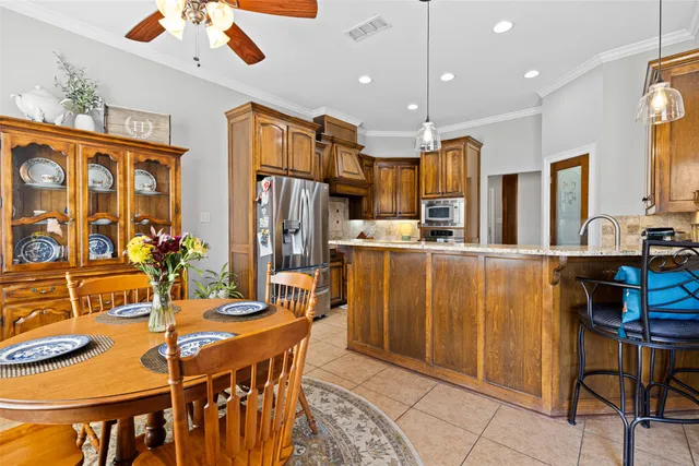 a dining room with stainless steel appliances kitchen island granite countertop a table chairs and a refrigerator
