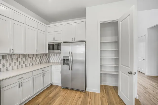 a kitchen with a refrigerator and white cabinets