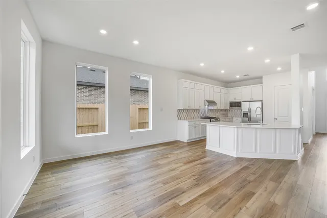 a open kitchen with white cabinets and wooden floor