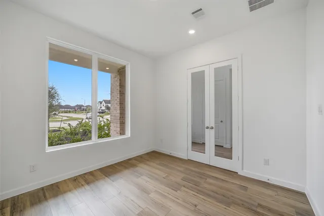 an empty room with wooden floor and windows